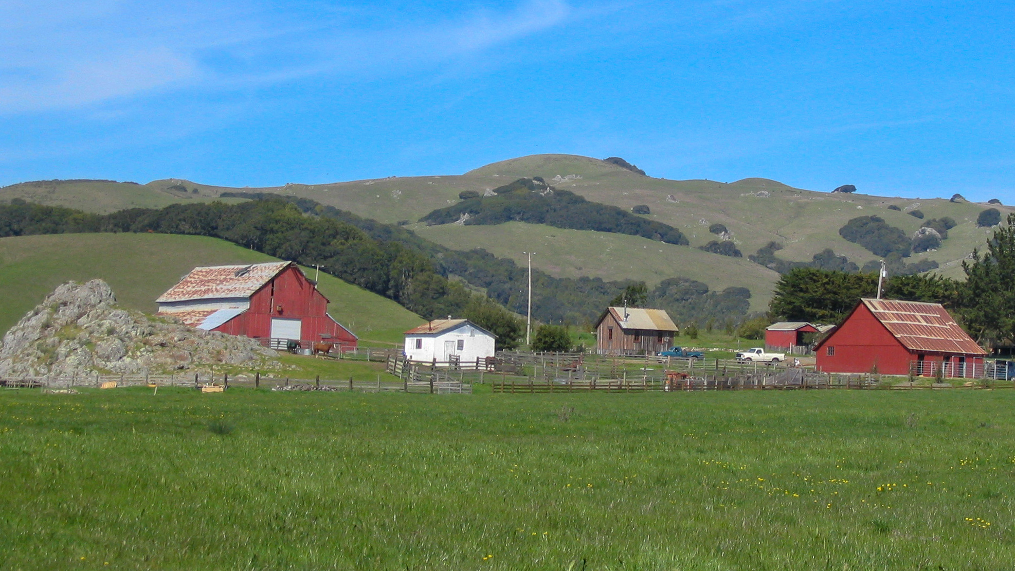 Farm with barn and other farm buildings near hills.
