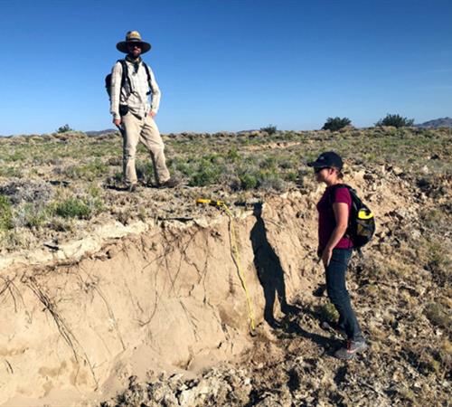 Two people standing next to an impressive fault scarp