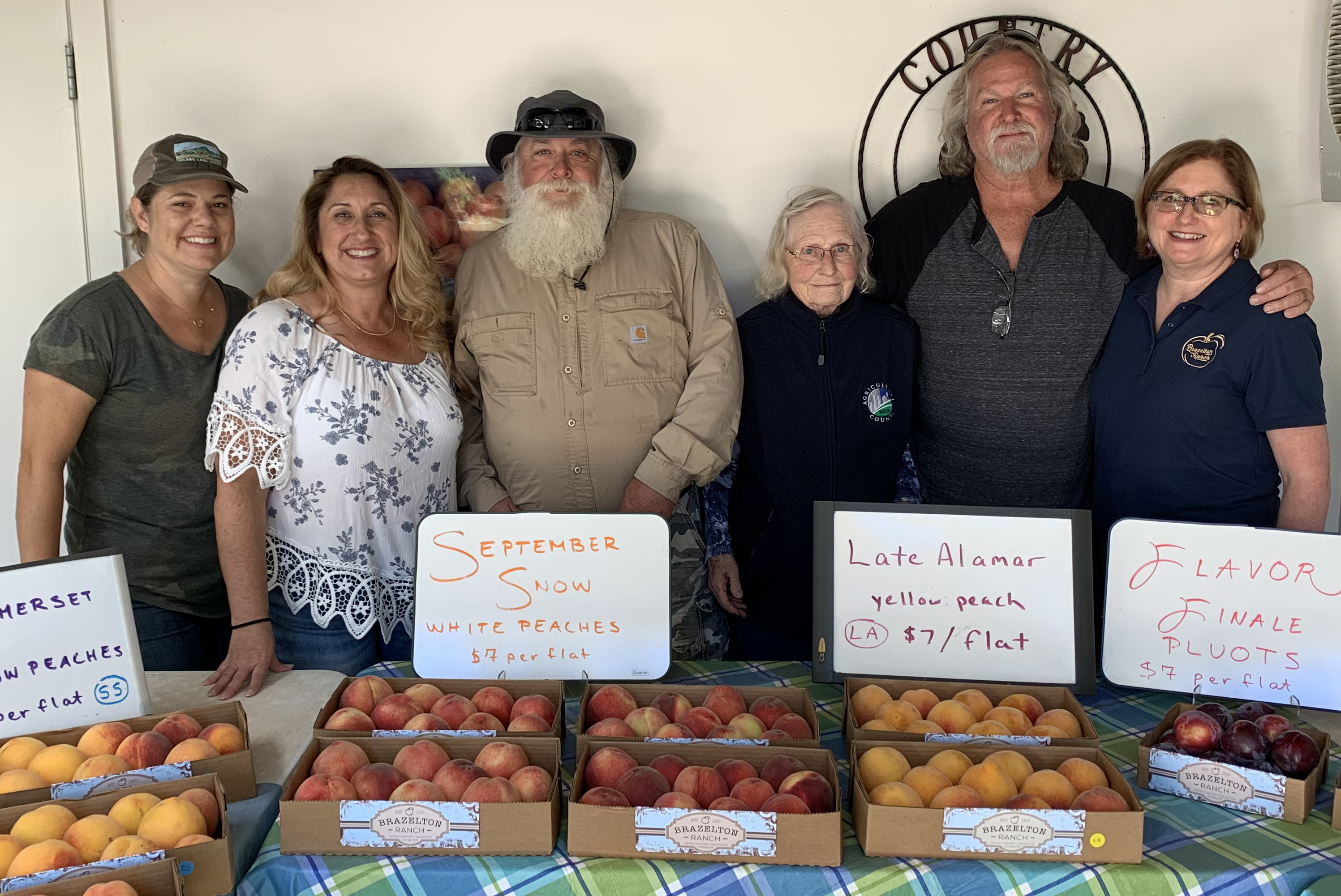 Brazelton family at their farmstand with baskets of fruit.