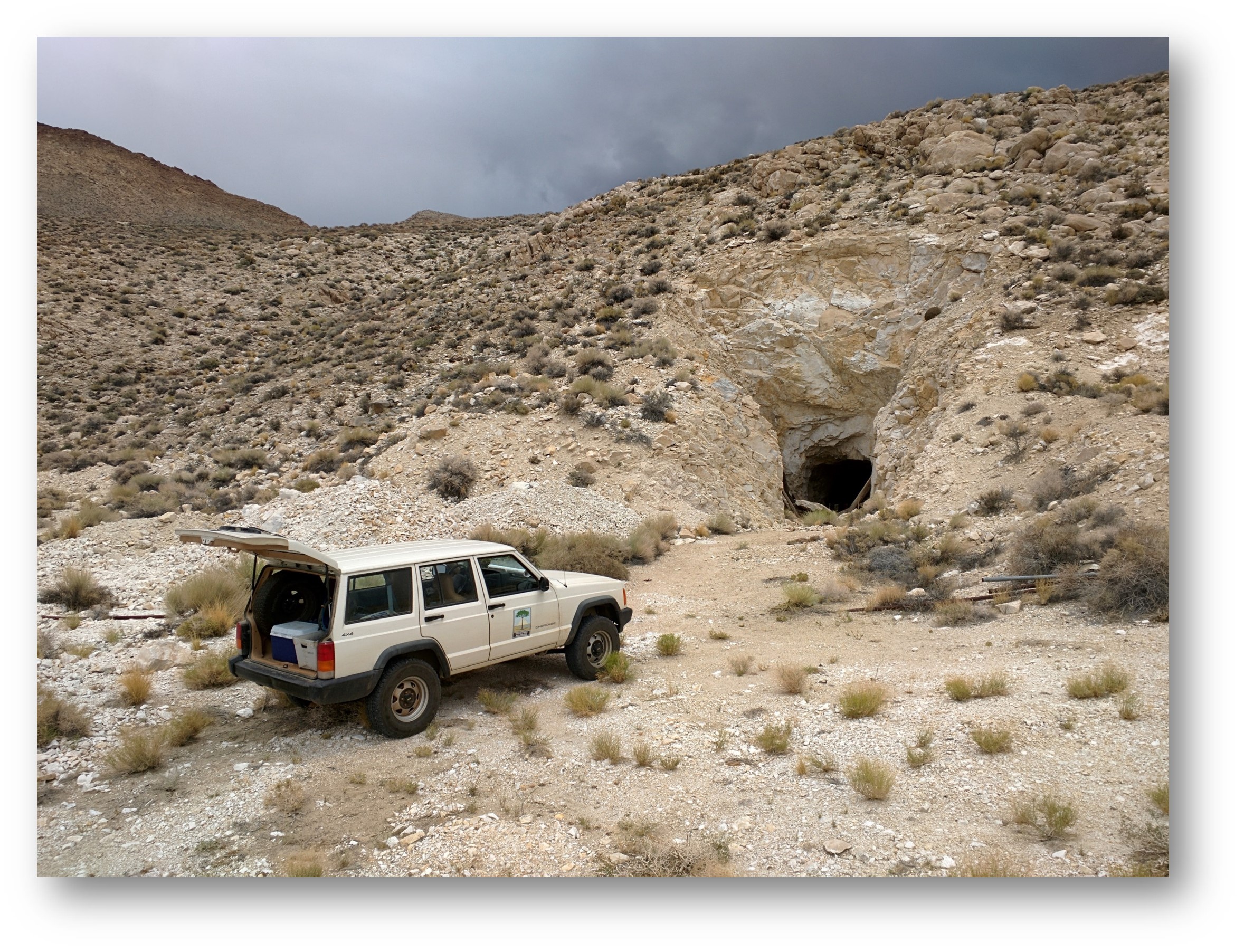 Desert landscape with Division of Mine Resources vehicle  parked outside entrance of an abandoned mine